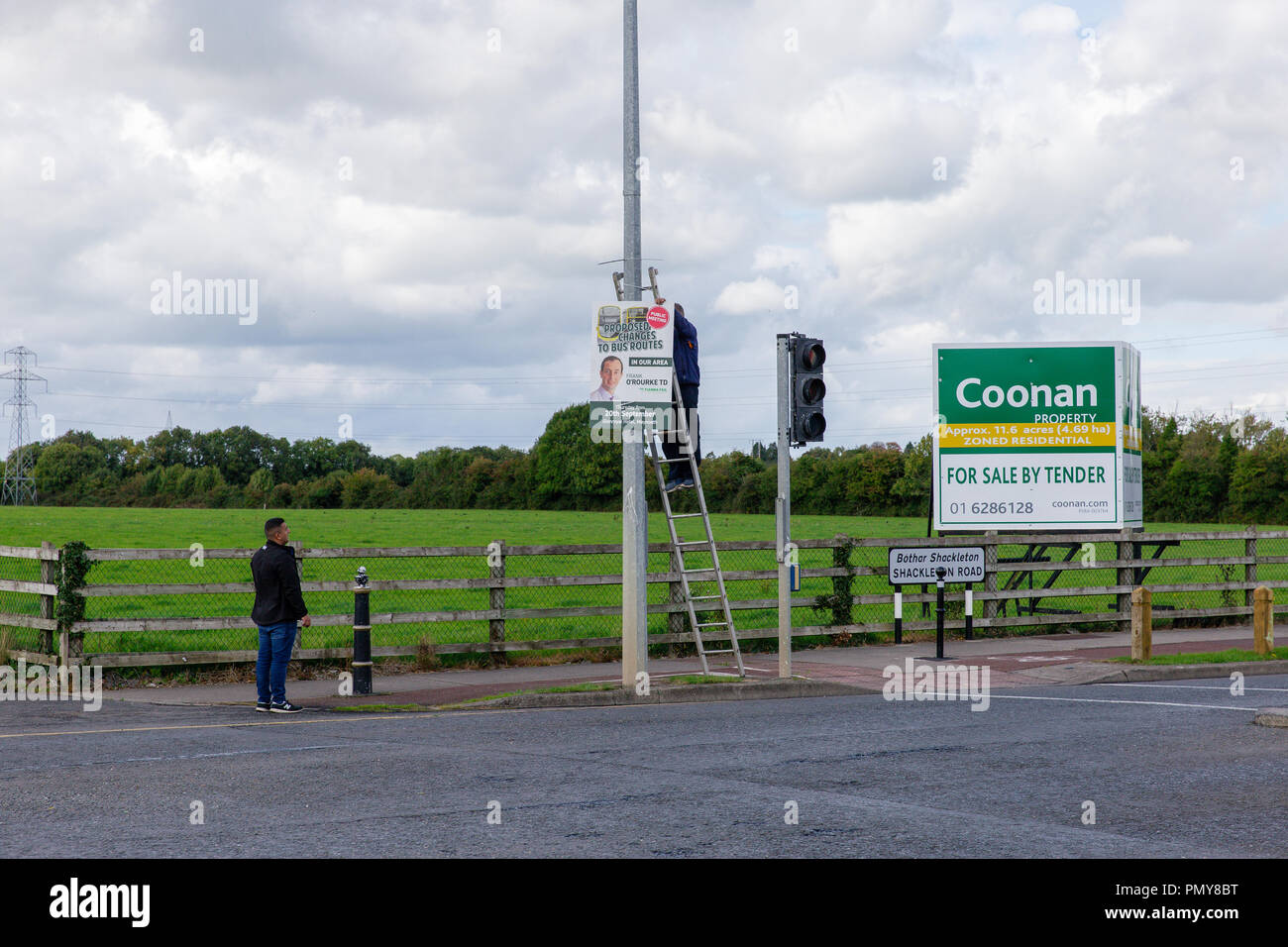 Celbridge, Ireland: Men hanging up a billboard advertising public meeting called by local TD Frank O`Rourke to discuss proposed changes to bus routes Stock Photo